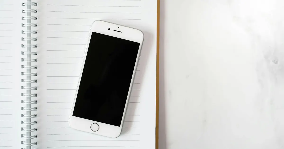 Notebook e celular mostram interfaces digitais em uma mesa.
