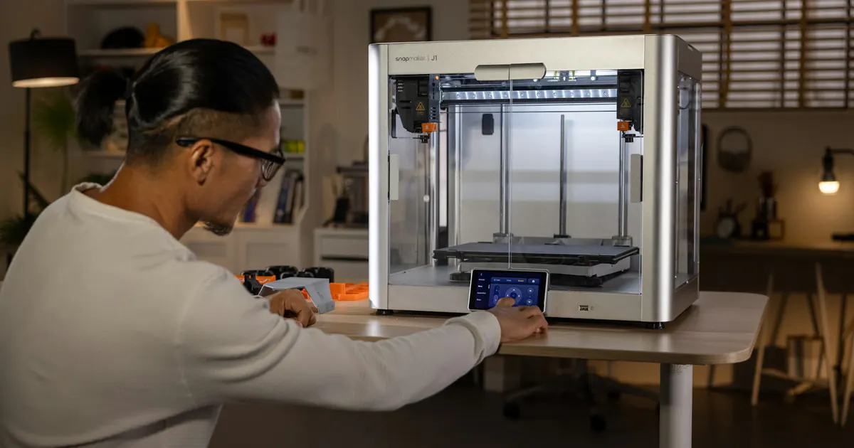 Pessoa ajusta uma impressora 3D durante a fabricação de uma peça.