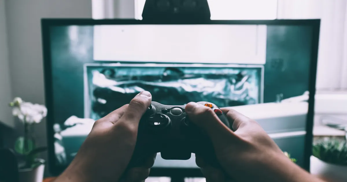 Jogador usa um controle diante de uma tela de videogame.