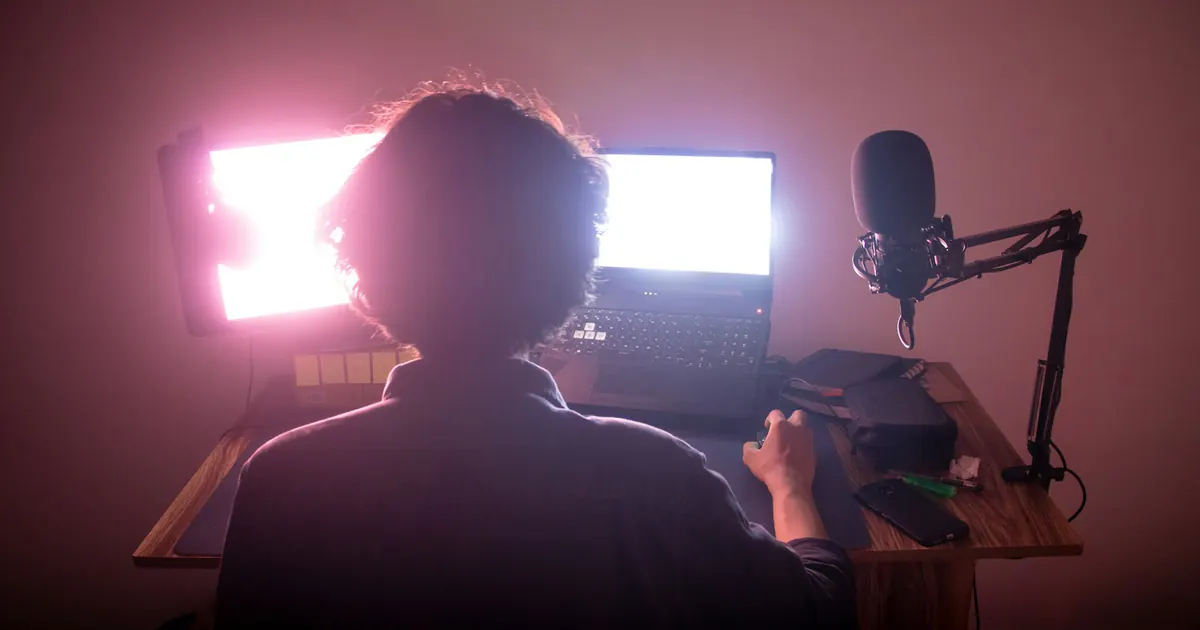 Pessoa trabalha diante de um computador com duas telas.