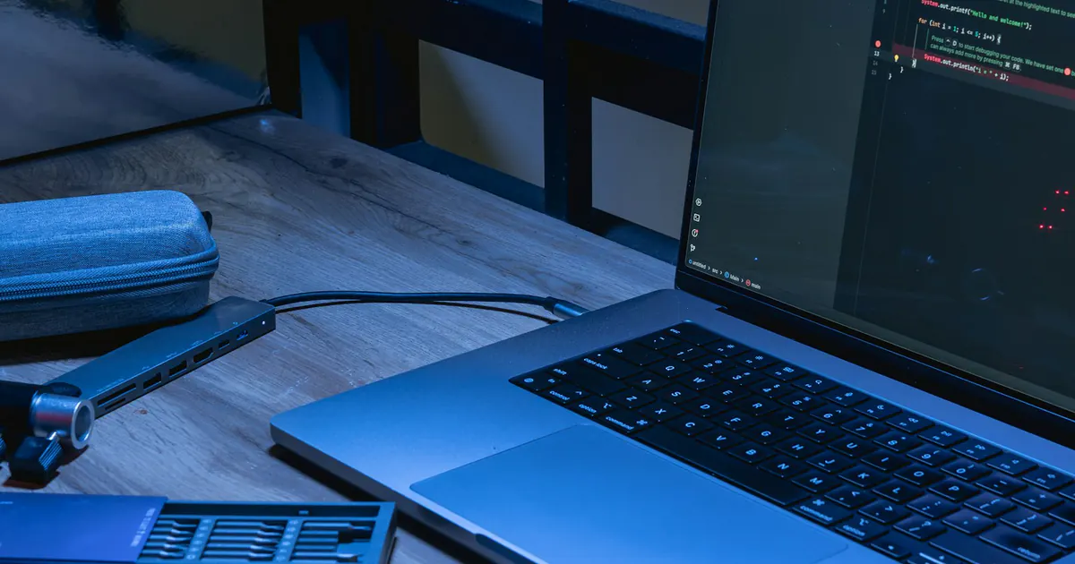 Notebook com código e celular sobre uma mesa de trabalho.