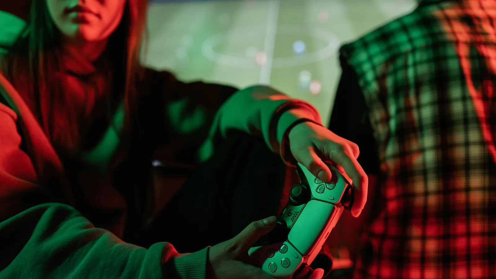 Pessoa segura um controle enquanto joga em um ambiente com iluminação colorida.