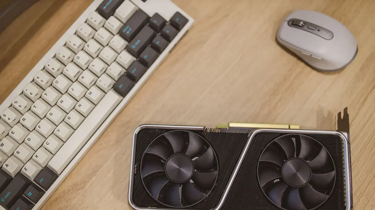 Placa de vídeo dedicada ao lado de teclado e mouse em uma mesa de trabalho.