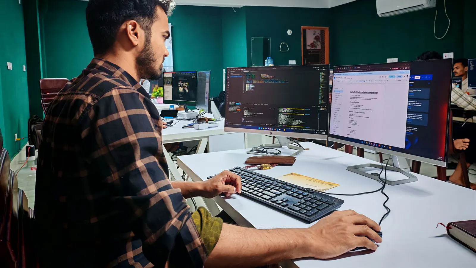 Desenvolvedor revisa código em dois monitores em um escritório iluminado.